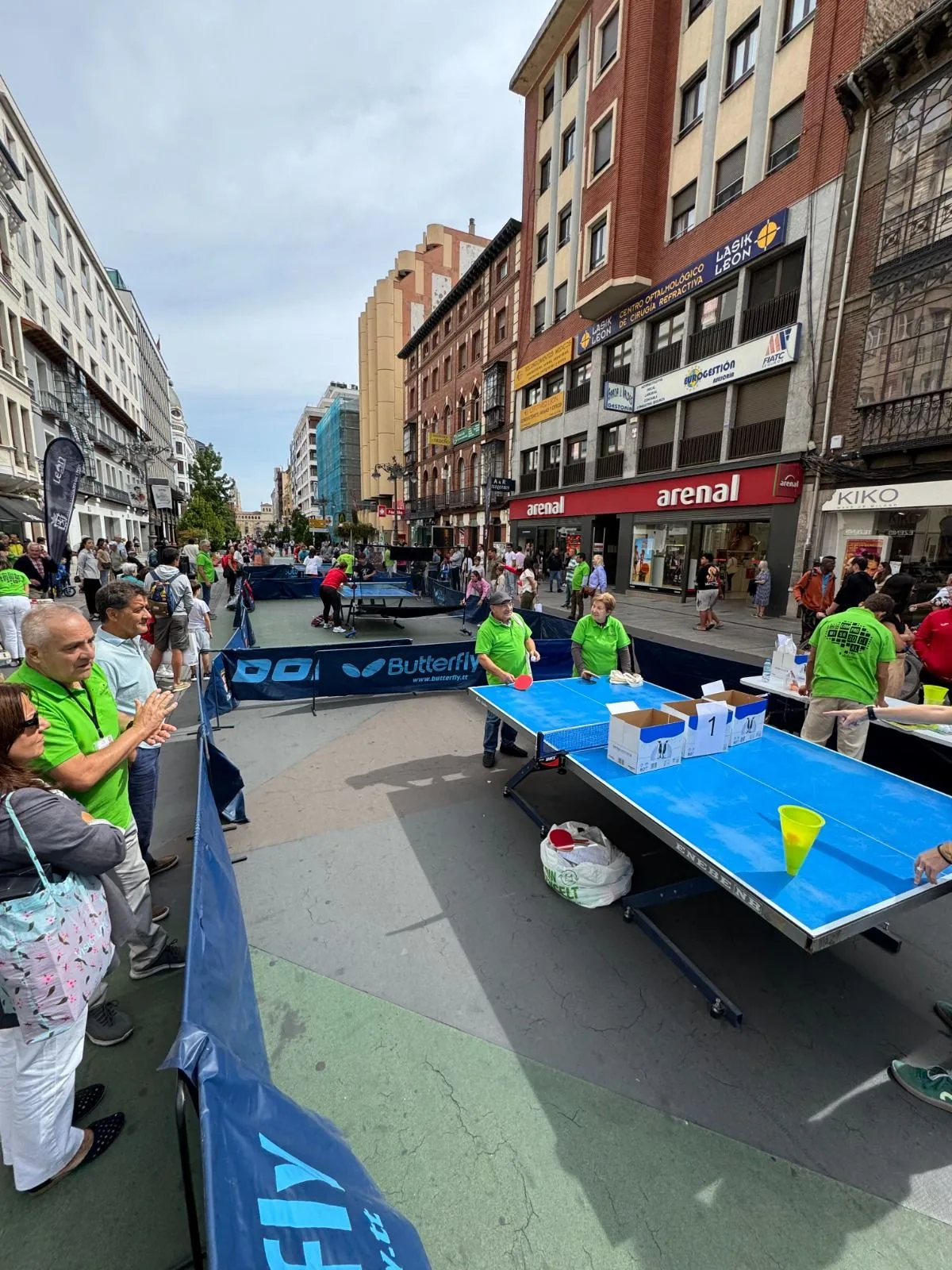 Tables set up along a pedestrian street in León with spectators watching